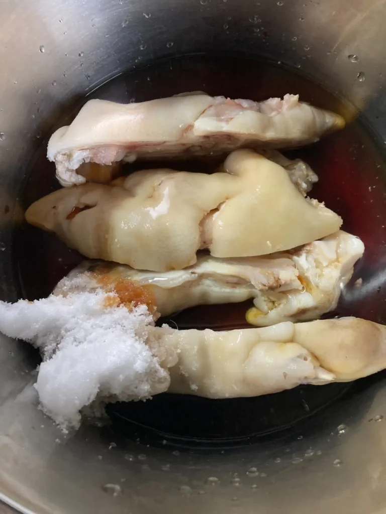 豚足を醤油・砂糖などの調味料に漬け込んで味付けしている下準備工程の写真