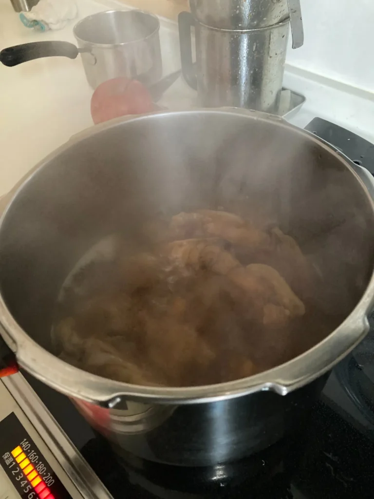 鍋で豚足をじっくり煮込み、柔らかくなるまで加熱している調理中の様子