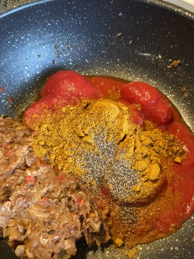 飴色玉ねぎのルーにトマトとカレー粉を加えて炒めている工程
