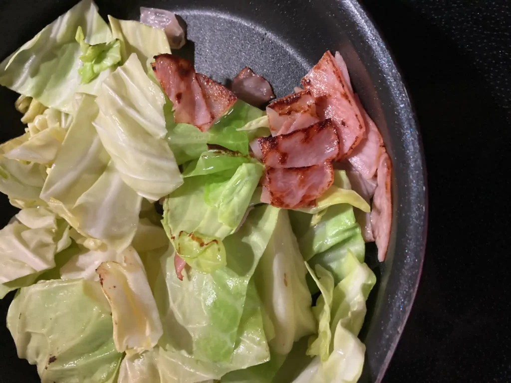 サンドイッチの具材としてキャベツとハムをフライパンで炒めている様子