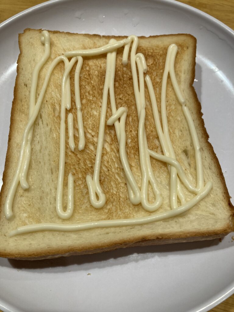 食パンにマヨネーズを塗りかけている写真