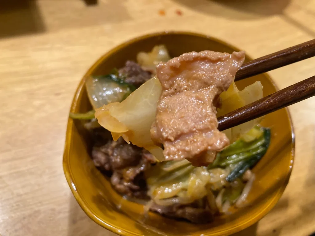 取り分けたチリトリ鍋の牛肉とキャベツを箸で持ち上げた様子