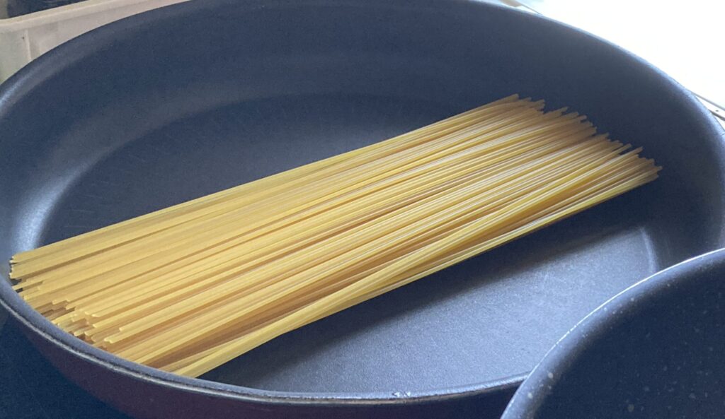 暗殺者のパスタでフライパンにパスタを入れる工程