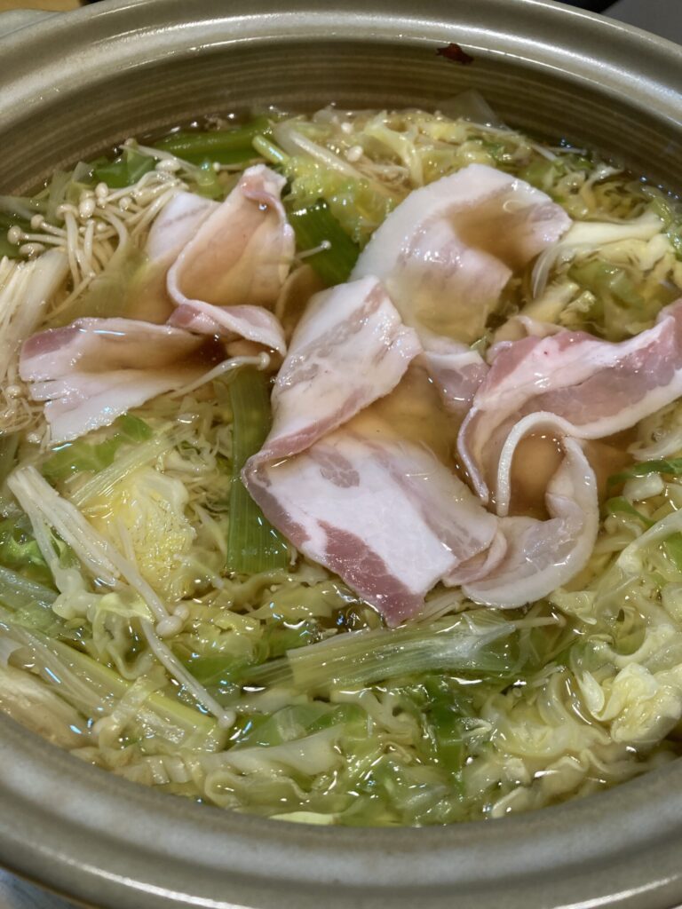 キャベツとネギの鍋に豚肉を入れてしゃぶしゃぶする様子
