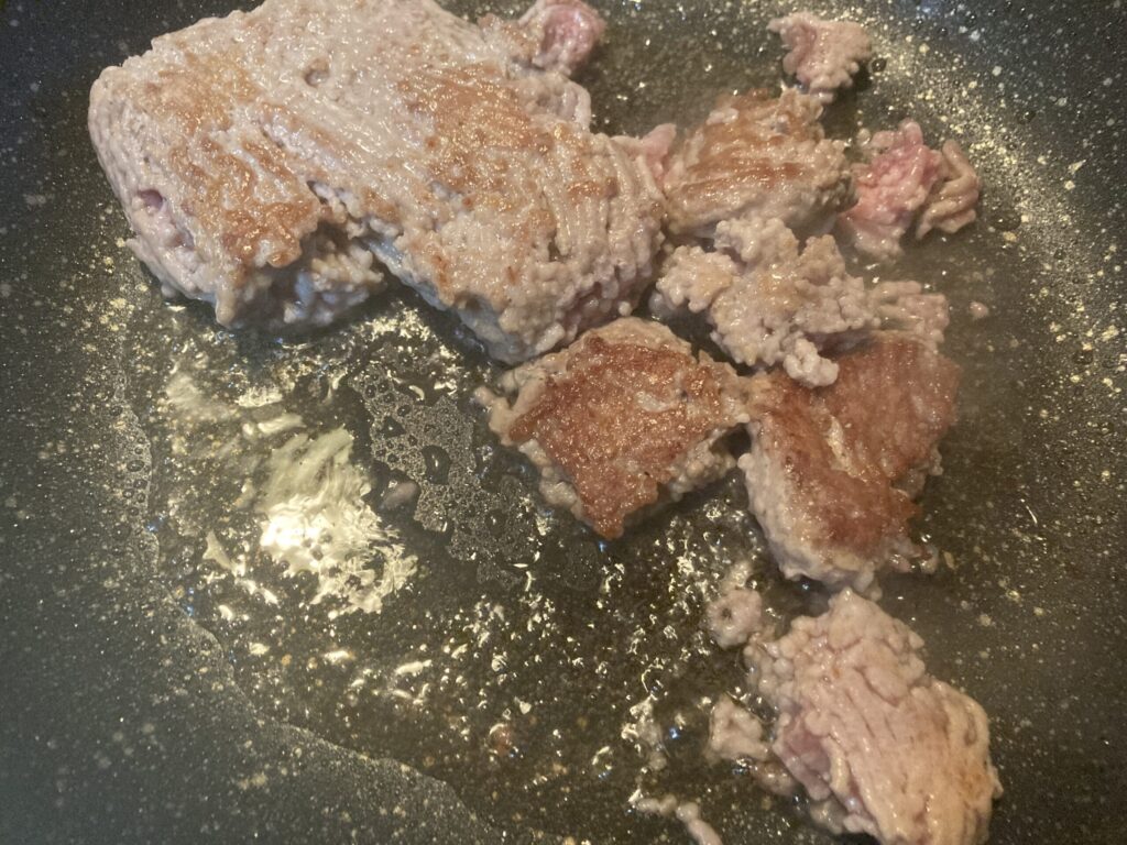 フライパンでごま油を使って豚ひき肉を炒めている様子