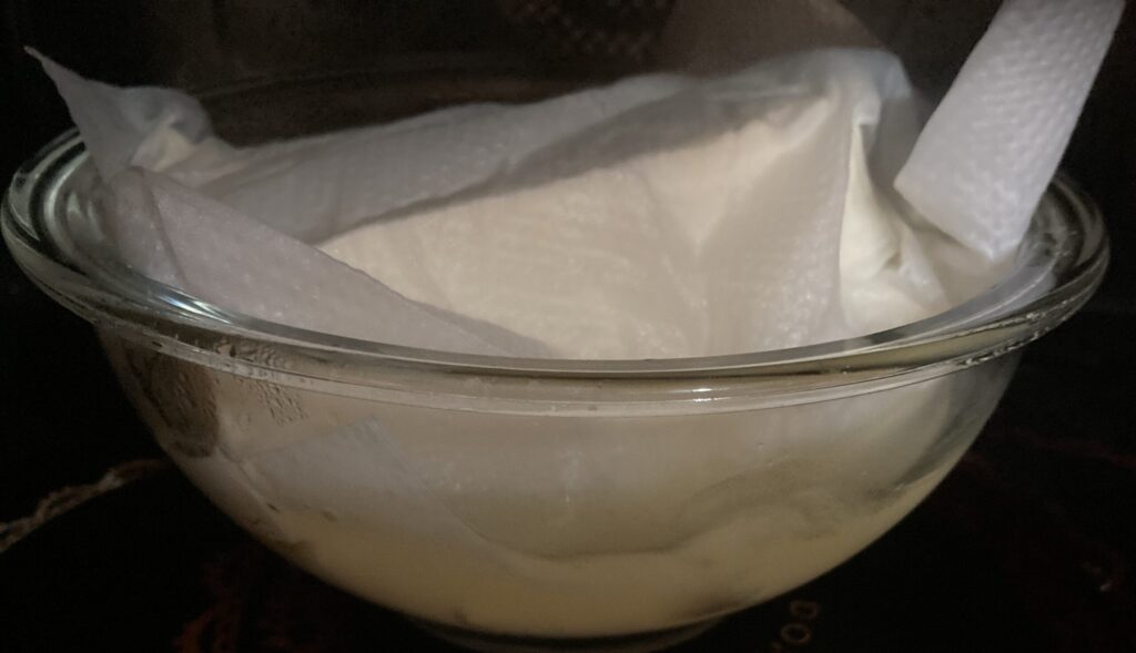 キッチンペーパーをかぶせた豆腐を耐熱ボウルに入れ電子レンジで水抜きしている様子