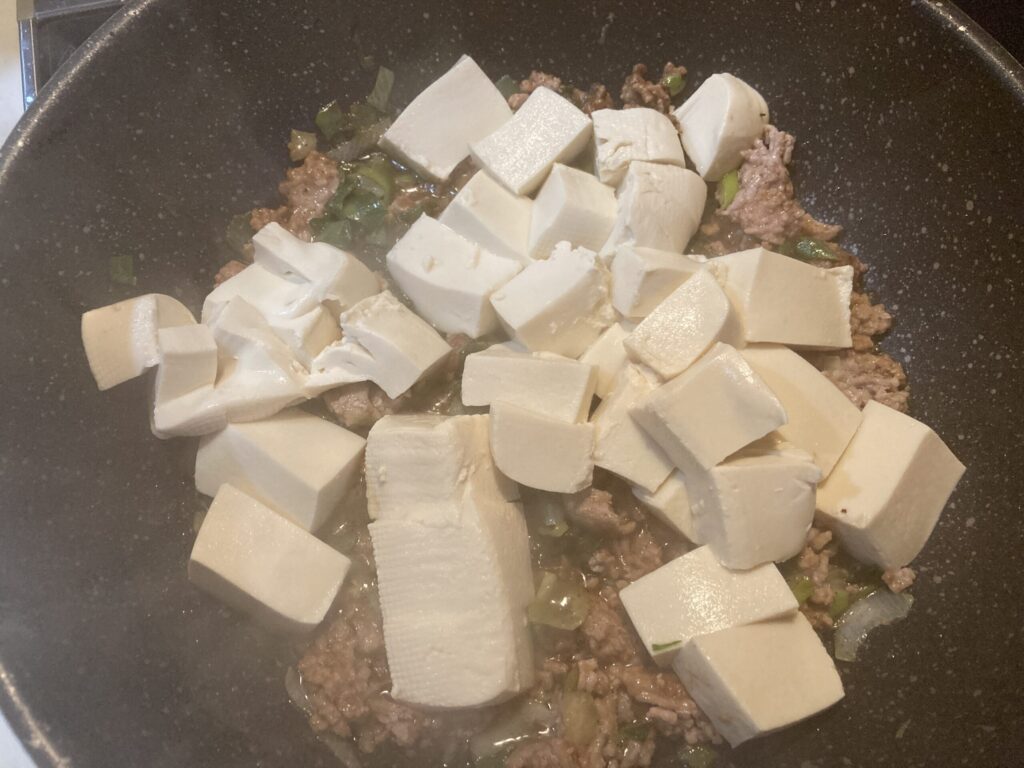 麻婆豆腐の調理でフライパンに豆腐を加えて炒めている様子