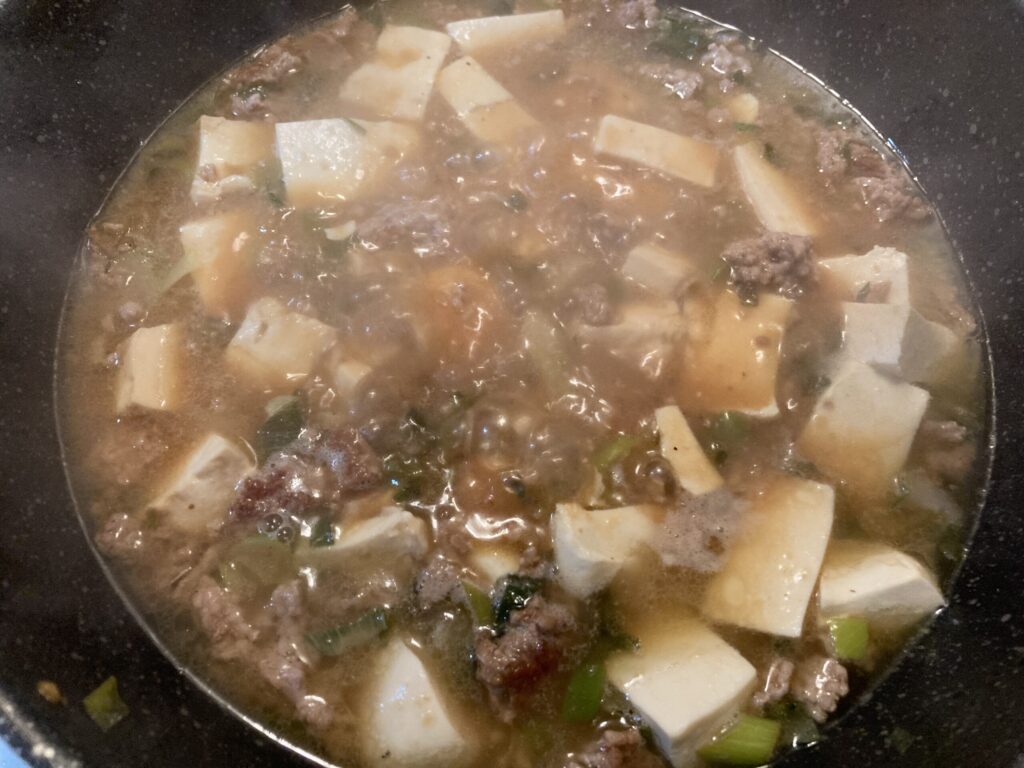 麻婆豆腐の調味料を加えて豆腐とひき肉を煮込んでいる様子