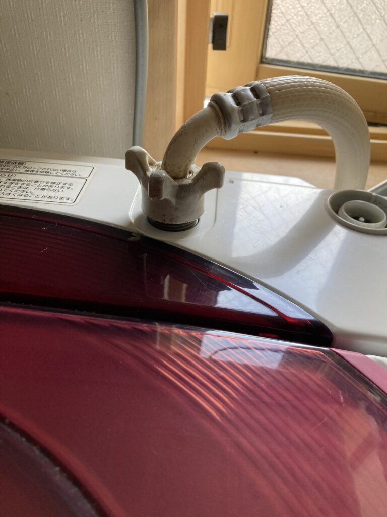 洗濯機の給水ホースを外す前にバルブを閉める様子