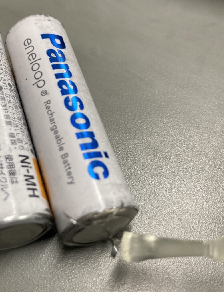 単三充電池のマイナス端子に接点復活剤を塗布している写真