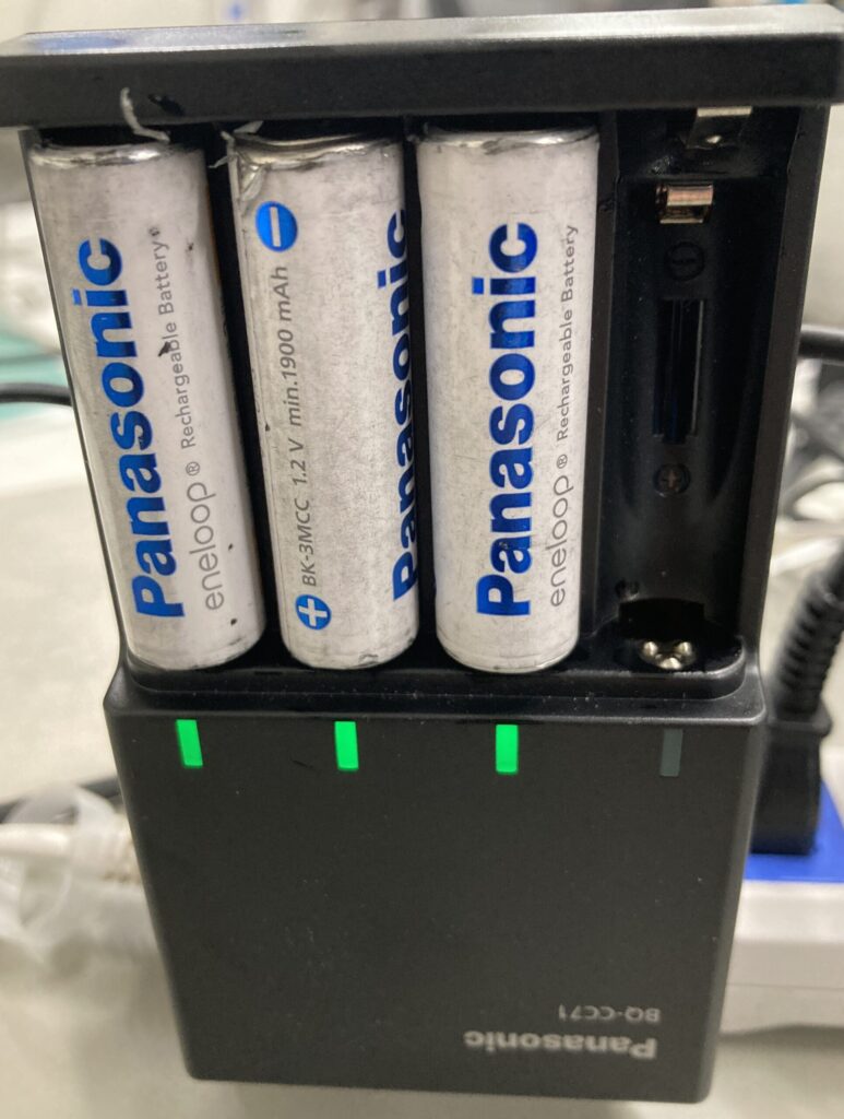 接点復活剤を塗布して清掃した後、Panasonicの単三電池を充電器にセットし、充電ランプが点灯して正常に充電できている様子の写真