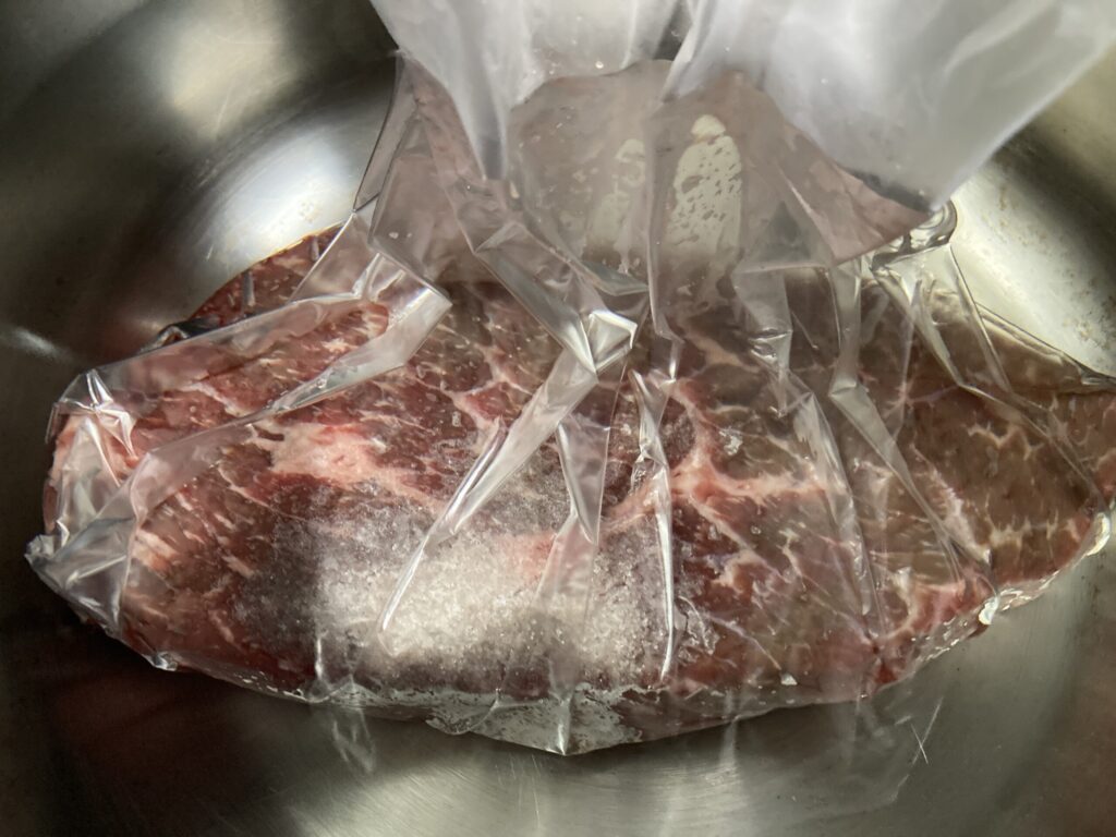 ポリ袋に入れた牛肉を水に沈めて空気を抜く低温調理の下準備方法