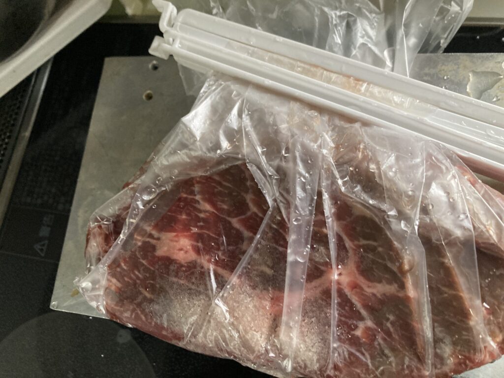 空気を抜いたポリ袋の口を袋クリップで固定する低温調理の密閉手順