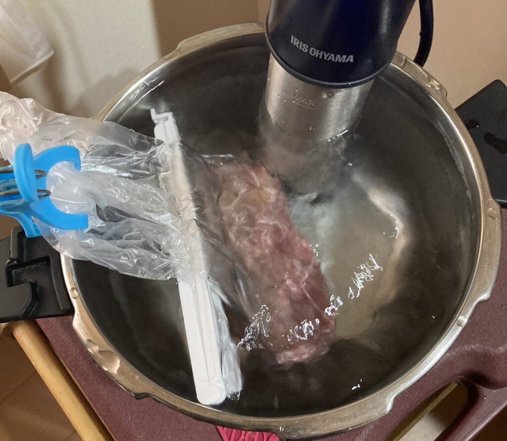 低温調理器で肉を真空袋に入れて湯せん加熱している様子 ローストビーフや鶏ハム調理