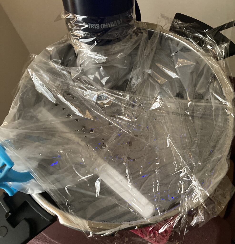 低温調理中に袋の口が水に入らないようラップで鍋を覆った状態