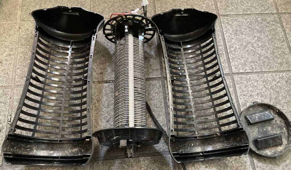 分解した電撃殺虫灯をブラシで掃除しながら掃除機で吸う様子