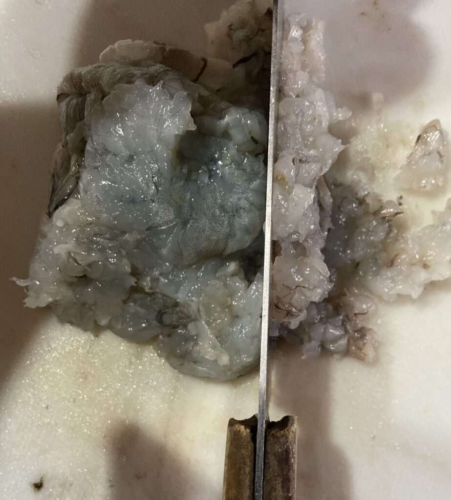 つぶしたエビを包丁で細かく刻んでシュウマイのタネにする