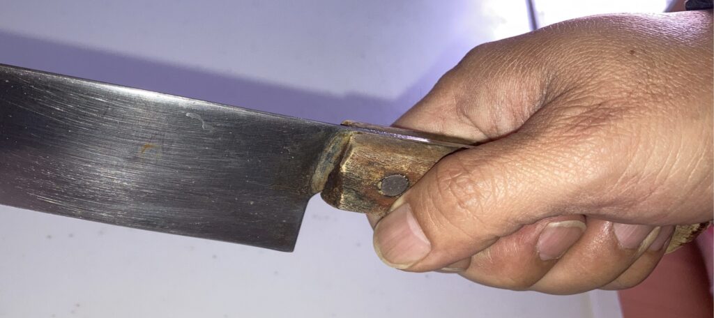 包丁の柄をしっかり握る持ち方（硬い食材用）を実演している手元の写真