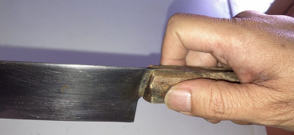 包丁の正しい持ち方（つまむ持ち方）を実演している手元の写真