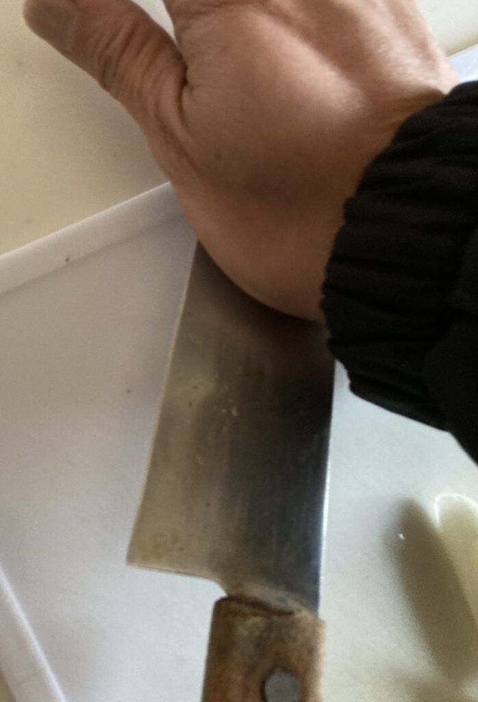 包丁の腹でにんにくを押しつぶしている手元の写真