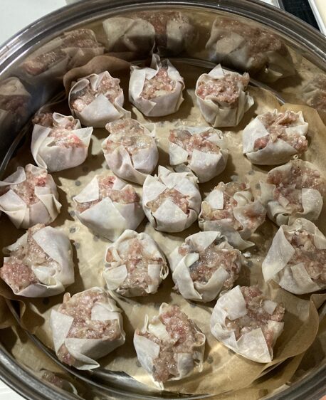 クッキングシートを敷いた蒸し器にシュウマイを並べる準備