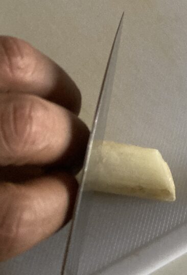 猫の手で食材を押さえ、指の関節をガイドにして包丁を当てている手元の写真