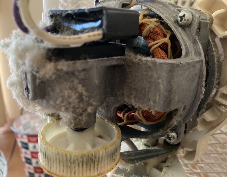 扇風機のモーター周辺に綿状のホコリが詰まっている様子