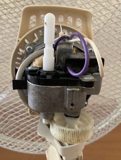 扇風機のモーター内部のホコリを雑巾で拭き取って掃除している様子