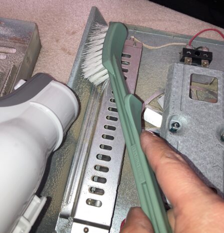 こたつヒーター内部のホコリをブラシと掃除機で掃除している様子