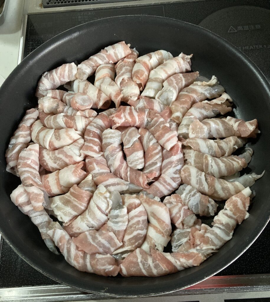 フライパンに並べた豚バラ巻きエビを中火で焼いている様子