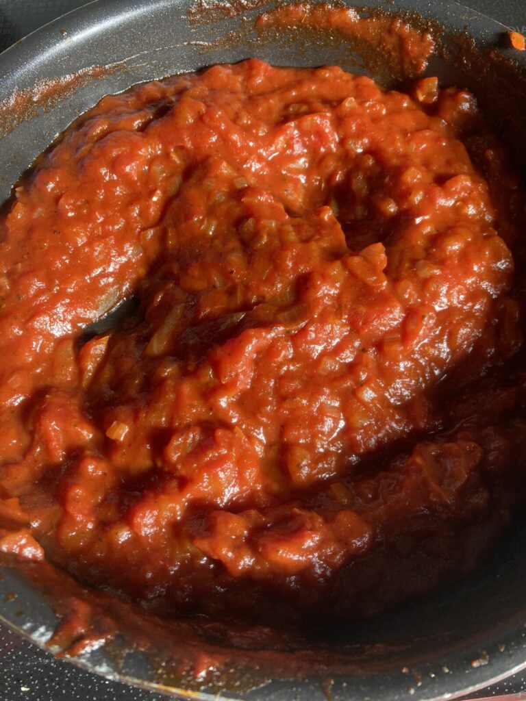 トマト缶と玉ねぎで作った手作りピザソースを煮詰めている様子（フライパン調理中）