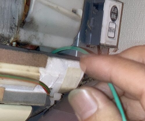 ドレンホースの奥までワイヤーブラシを入れて汚れをかき出している様子