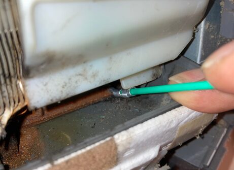 ドレンホース内部にブラシを差し込み清掃している様子