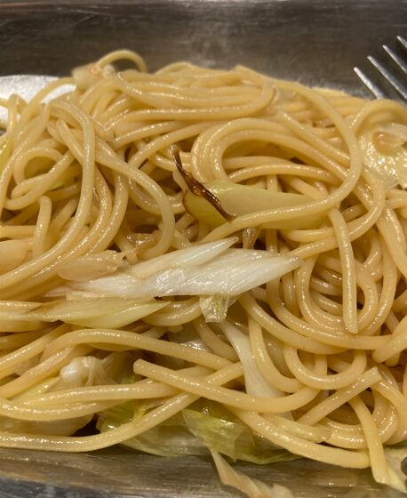 パスタと野菜を調味料で混ぜ合わせて仕上げている様子
