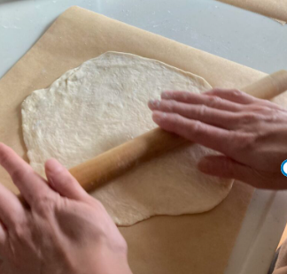 ピザのクリスピー生地を麺棒で均一に薄く広げている作業風景（パリパリにする工程）