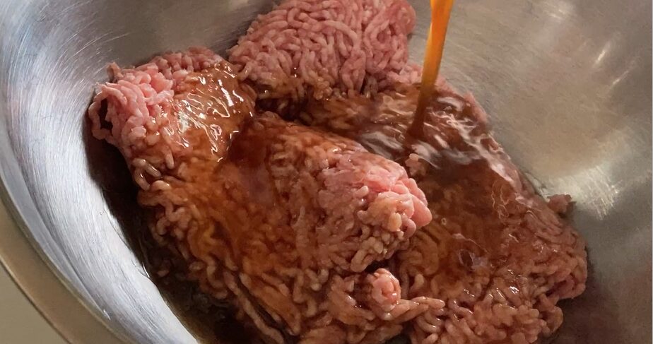 ひき肉に調味料を掛けている