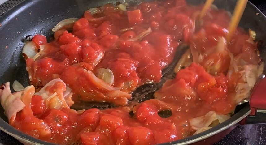 トマト缶を入れて炒めている